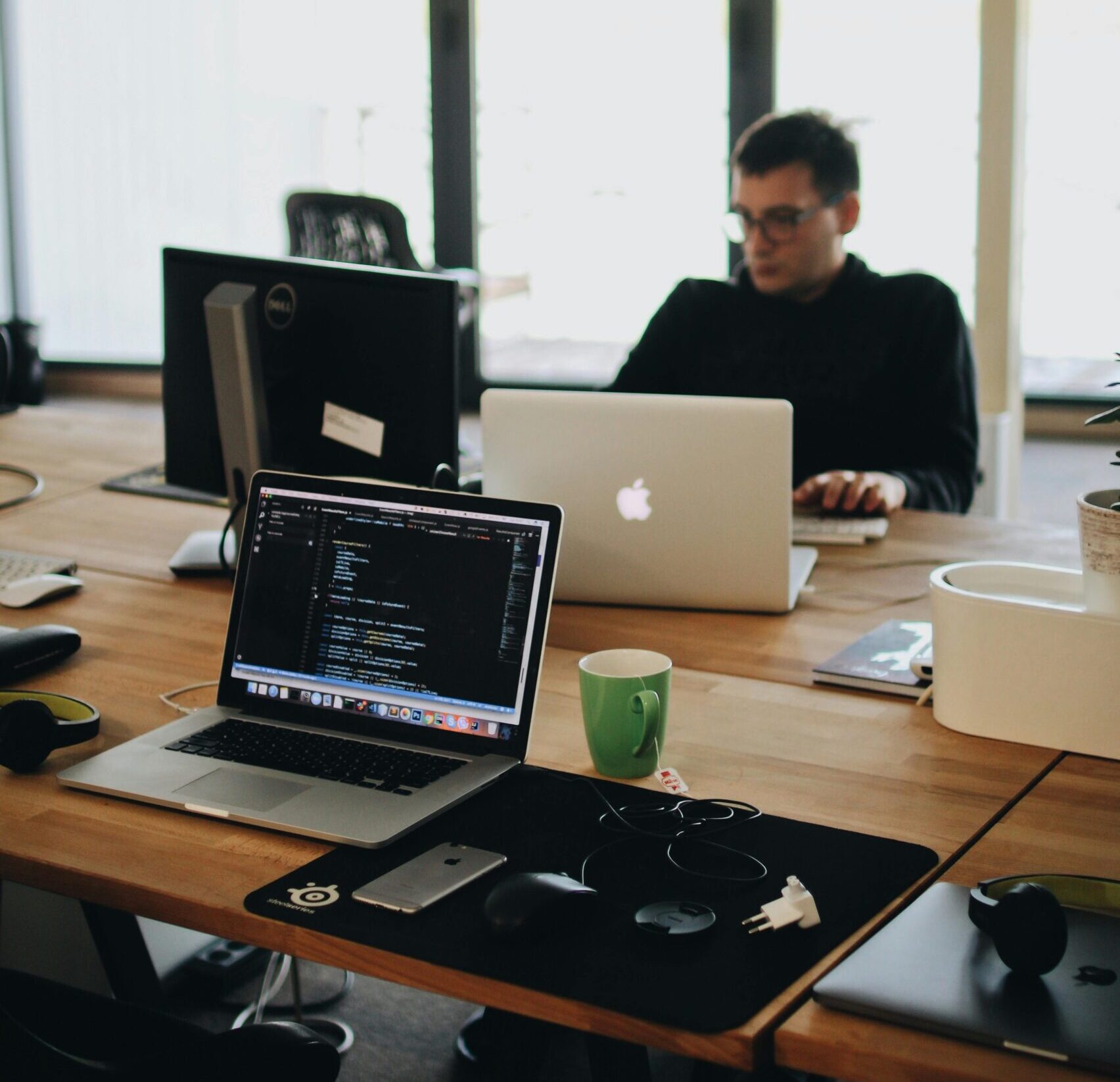 A web developer working on code in a modern office setting with multiple devices.